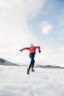 Rear view of girl with running across snow field. — Stock Photo