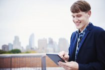 Junger Mann steht auf Dach und blickt auf digitales Tablet. — Stockfoto