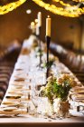 Wedding venue decorated for party with fairy lights and long table set. — Stock Photo