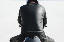 Hombre de cuero negro sentado en motocicleta en Bonneville Salt Flats, Utah, EE.UU. - foto de stock