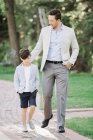 Father with elementary age son walking along path in garden. — Stock Photo