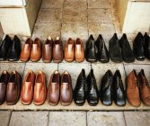 Rows of black and brown leather shoes on front steps of building. — Stock Photo