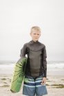 Loira menino de pé na praia de areia e segurando bodyboard . — Fotografia de Stock