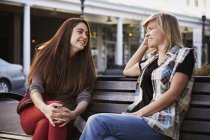 Two women sitting and talking on bench in urban street. — Stock Photo