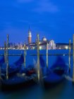 Gondole ormeggiate a riva con vista sull'isola e sulla chiesa di San Giorgio Maggiore al tramonto, Venezia . — Foto stock