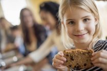 Elementary menina idade segurando biscoito na cozinha . — Fotografia de Stock