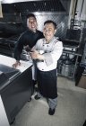 Двоє чоловіків-кухарів позують на комерційній кухні ресторану . — стокове фото