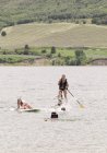 Teenage girls stand up paddle surfing on water of lake. — Stock Photo