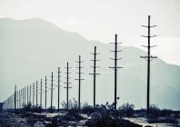 Power lines reaching into distance with mountains silhouettes. — Stock Photo