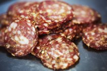 Close-up of sliced salami on black background. — Stock Photo