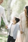 Father, mother and son walking and holding hands in park. — Stock Photo