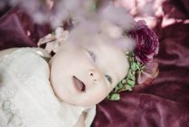Portrait de bébé fille souriante avec couronne de fleurs sur la tête . — Photo de stock
