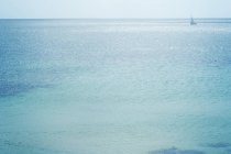 Vista a distanza della barca a vela sul mare blu scintillante
. — Foto stock