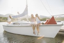 Irmãs adolescentes sentadas com os pais em um veleiro no lago . — Fotografia de Stock