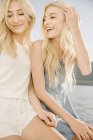 Portrait of two blonde sisters laughing on sailboat on lake. — Stock Photo