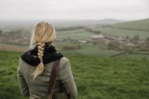 Rear view of woman standing in hilltop and looking at view. — Stock Photo
