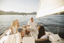 Mature parents and teenage daughters relaxing on sailboat on lake. — Stock Photo