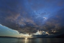 Puesta de sol y paisaje nublado sobre la calma de la superficie del mar . - foto de stock