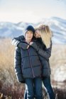 Woman hugging son in jacket and woolly hat outdoors. — Stock Photo