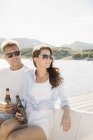 Hombre y mujer sentados en velero y tomando cerveza . - foto de stock