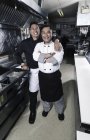 Deux cuisiniers masculins posant dans la cuisine du restaurant commercial
. — Photo de stock