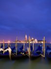 Gondole ormeggiate a riva con vista sull'isola e sulla chiesa di San Giorgio Maggiore al tramonto, Venezia . — Foto stock