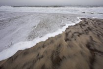 Волны кружатся на берегу на песчаном пляже . — стоковое фото