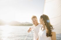 Uomo e donna in piedi e sorridenti mentre si guardano a vicenda in barca a vela . — Foto stock