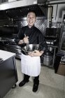 Male cook stirring in mixing bowl in commercial restaurant kitchen. — Stock Photo