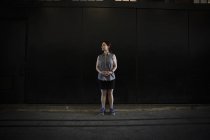 Жінка в без рукавів сорочці та шортах з кросівками, стоячи в тіні, будуючи на вулиці . — стокове фото