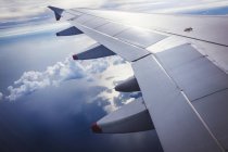 Wing of airplane in flight against blue sky with clouds. — Stock Photo