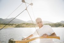Homem maduro com óculos de sol dirigindo veleiro no lago . — Fotografia de Stock