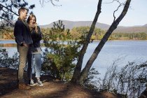 Man and woman standing on shore of lake in autumn. — Stock Photo