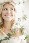 Blonde woman smiling with leafy garland around shoulders. — Stock Photo