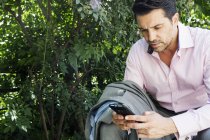 Businessman in grey suit and pink shirt sitting outdoors and using phone. — Stock Photo