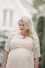 Porträt einer schwangeren Frau mit langen blonden Haaren im Garten. — Stockfoto