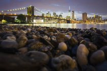Vista noturna para Manhattan com a Ponte Manhattan atravessando o rio, Nova York, EUA . — Fotografia de Stock