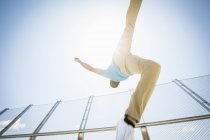 Young man somersaulting on city bridge, low angle view. — Stock Photo