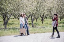 Female photographer taking pictures of women in orchard in summer. — Stock Photo