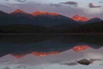 Montañas rocosas canadienses con luz solar reflejándose en el agua del lago . - foto de stock