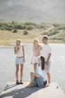 Genitori maturi con figlie adolescenti che si rilassano sul molo del lago . — Foto stock