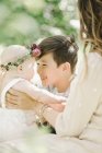 Woman and preteen boy greeting baby girl outdoors. — Stock Photo