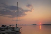 Pôr do sol sobre o Mar Mediterrâneo com iate ancorado na costa . — Fotografia de Stock