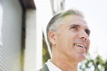 Man with grey hair standing on street, looking up and smiling. — Stock Photo