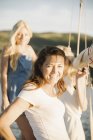 Mature woman with blonde daughters on sailboat in sunlight. — Stock Photo