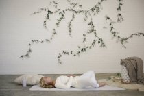 Mujer rubia descansando sobre una esterilla de yoga blanca . - foto de stock