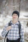 Male hiker in woolly hat holding backpack outdoors. — Stock Photo