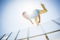 Jeune homme sautant sur le pont de la ville, vue à angle bas . — Photo de stock
