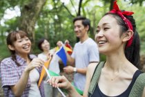 Group of friends holding flags at outdoor party in forest. — Stock Photo