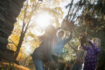 Children playing outdoors and throwing fallen leaves in autumn sunshine. — Stock Photo
